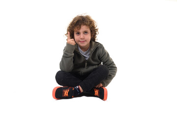 front view of  boy dressed in sportswear sitting on the floor looking at camera pointing up on  white background