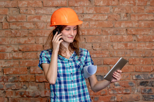 A woman wearing an orange hard hat talking on a cell phone