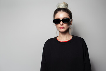 Portrait of beautiful girl with hair bun wearing sunglasses and sweater.