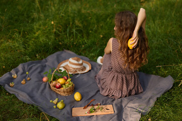 Aerial view of woman enjoying picnic with fruits and hat