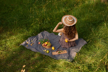 Stylish woman relaxing outdoors amid fresh fruit and warm sun