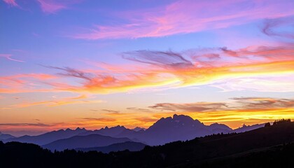 A dramatic sunset paints the sky with vibrant hues of pink, orange, and yellow, casting silhouetted mountain ranges against the colorful backdrop.