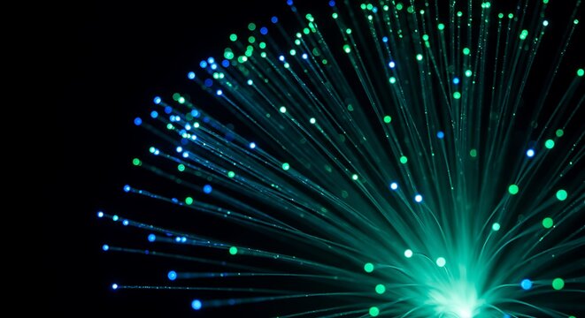 Closeup of glowing fiber optic strands emitting vibrant green and blue light against a dark background, representing data transfer and connectivity - Powered by Adobe