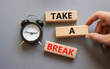 Take a break symbol. Concept words Take a break on wooden blocks. Businessman hand. Beautiful grey background with alarm clock. Business and Take a break concept. Copy space.
