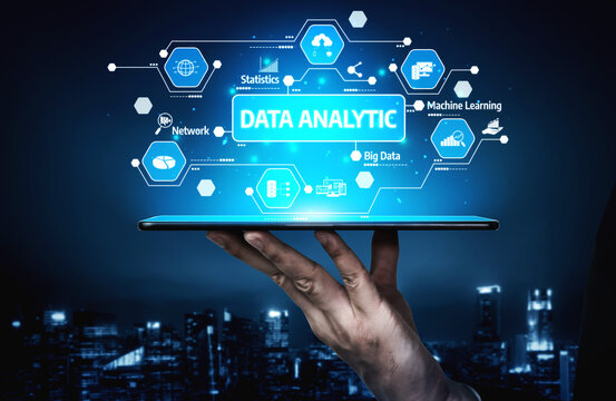 A hand holds a digital tablet displaying futuristic data analytic concepts and graphics against a stunning night cityscape, representing technology and innovation. Tessel - Powered by Adobe