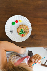 Kids decorating a large round cookie with edible paints and brushes during a tropical Christmas creative activity, painting festive designs like trees and ornaments, fun DIY holiday food art workshop