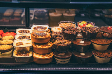 Assorted layered desserts displayed in a refrigerated showcase inside a pastry shop
