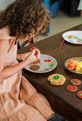 Kids decorating a large round cookie with edible paints and brushes during a tropical Christmas creative activity, painting festive designs like trees and ornaments, fun DIY holiday food art workshop