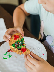 Kids decorating a large round cookie with edible paints and brushes during a tropical Christmas creative activity, painting festive designs like trees and ornaments, fun DIY holiday food art workshop