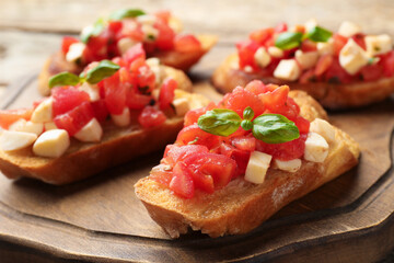 Tasty bruschettas with mozzarella cheese, tomatoes and basil on table, closeup