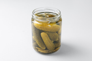 Pickled cucumbers in jar on light background, closeup