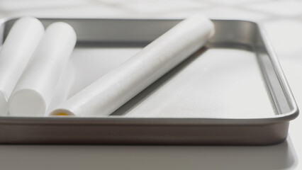 White parchment paper rolls rest on a clean metal baking tray.
