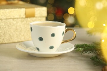Aromatic coffee and Christmas decor on white wooden table against blurred lights, closeup