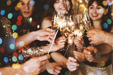 Happy New Year 2026 greeting card, bokeh lights. Friends celebrating with sparklers and wine glasses