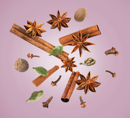 Christmas spices falling on dusty pink background