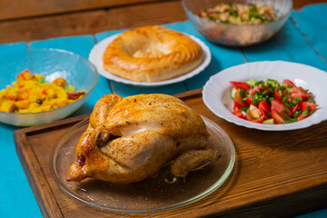 Couscous with dried hands and turmeric, whole baked chicken on a wooden tray, flatbread