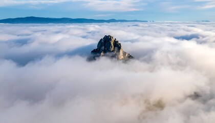 Lone mountain peak rising above foggy clouds