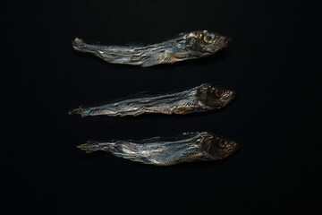 Three Dried Sprats in a Neat Vertical Stack Against a Black Backdrop — Minimalist Still Life Photography
