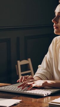 Lady working quietly, Woman engrossed in editing notes under dim lighting environment, Female researcher focused on revising documents amidst subdued study ambiance with deadline pressure