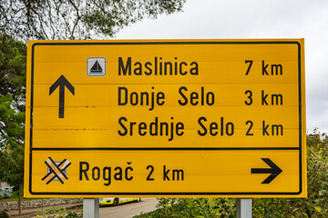 Bright Yellow Road Sign With Distances To Croatian Towns Along A Coastal Road, Grohote, Croatia