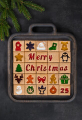 Merry Christmas. 25 cookies. On a wooden board. Dark background. Decorated with branches of a Christmas tree. Top view	