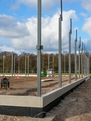Naklejka premium Steel structural columns installed on concrete foundation at early-stage construction site
