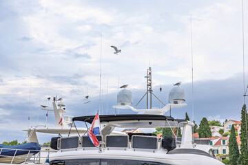 Luxurious Yacht in Harbor With Seagulls, Croatian Flag, and Overcast Sky