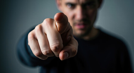Man pointing with an accusatory gesture in dark atmospheric setting  