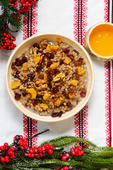 Traditional Christmas Ukrainian wheat kutia with dried fruits, honey and poppy seeds on a Christmas rustic background