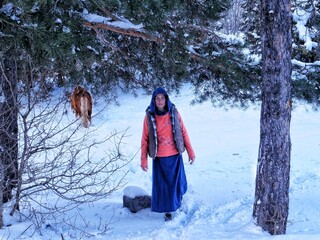 A young woman is walking in the snow with a horse behind her. Georgia - February 2025.