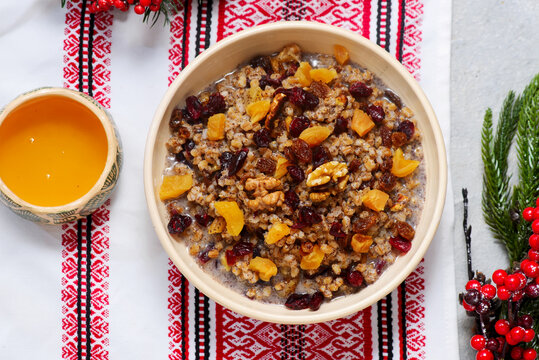 Traditional Christmas Ukrainian wheat kutia with dried fruits, honey and poppy seeds on a Christmas rustic background