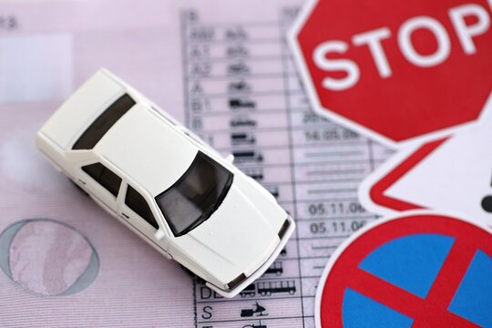Driving school concept. Toy car and road signs on driver license close up