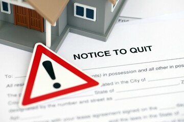 Generic toy house and eviction notice or notice to quit on table close up