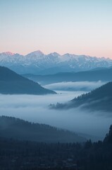 Obraz premium The mountains are covered in fog and the sky is a beautiful shade of blue