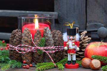 Weihnachtsdekoration mit Nussknacker, Tannenzapfen und roter Kerze	