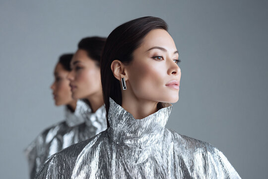 Elegant portrait of woman in a silver futuristic garment, showcasing minimalist jewelry. Represents beauty, individuality, strength and forwardthinking concepts. Great for fashion, tech, and beauty.