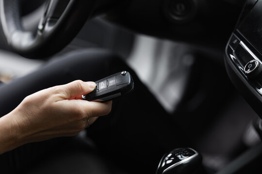 Woman using car key fob inside vehicle with modern dashboard and interior design elements