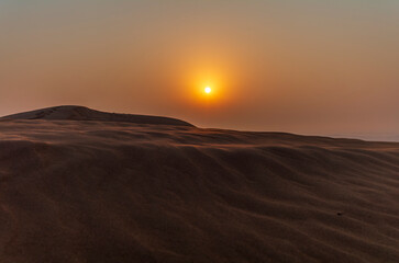 The sun rising on the pristine and untouched red dunes in the desert near Dubai