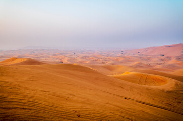 The sun rising on the pristine and untouched red dunes in the desert near Dubai