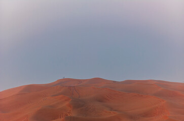 People standing on the red dunes in the desert near Dubai waiting for the sunrise