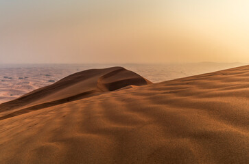 The sun rising on the pristine and untouched red dunes in the desert near Dubai