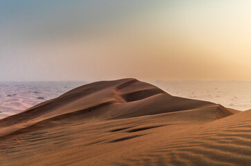 The sun rising on the pristine and untouched red dunes in the desert near Dubai
