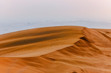 The sun rising on the pristine and untouched red dunes in the desert near Dubai