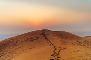 The sun rising on the pristine and untouched red dunes in the desert near Dubai