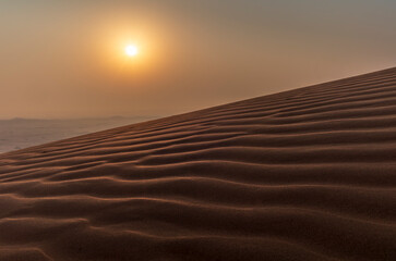 Sand waves on the red dunes in the desert near Dubai at sunrise
