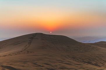 The sun rising on the pristine and untouched red dunes in the desert near Dubai