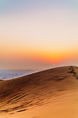 The sun rising on the pristine and untouched red dunes in the desert near Dubai