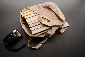 Vista superior com câmera analógica ao lado de livros enfileirados sobre fundo escuro com espaço...