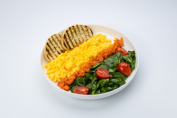 Scrambled eggs with smoked salmon, sauteed spinach and toast, studio top view