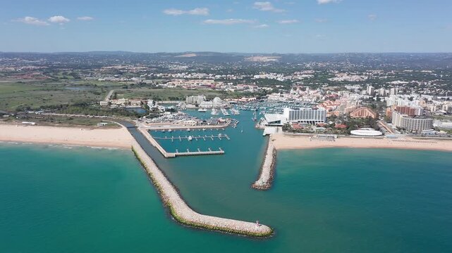 Vilamoura aerial view aerial view vilamoura marina entrance with twin breakwaters guiding turquoise channel into protected harbor, beach shoreline, calm waters, scattered yachts, coastal